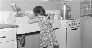 child washing her hands at the kitchen sink, 1930s