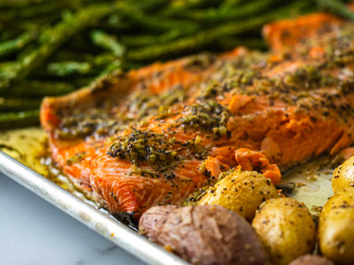 Close up of salmon, potatoes, and greens on a sheet pan