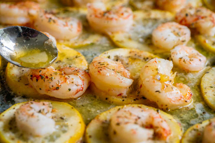 Close up of seasoned shrimp on top of lemon slice on a sheet pan