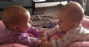 twin babies talking and holding hands