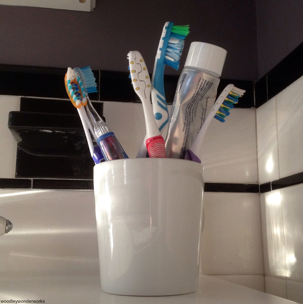 toothbrush holder filled with toothbrushes and toothpaste