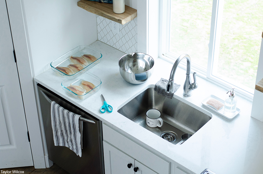 kitchen sink with raw chicken being prepared nearby