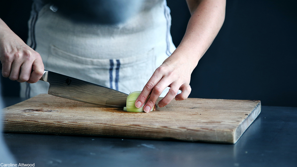 person chopping vegetables on a cutting board