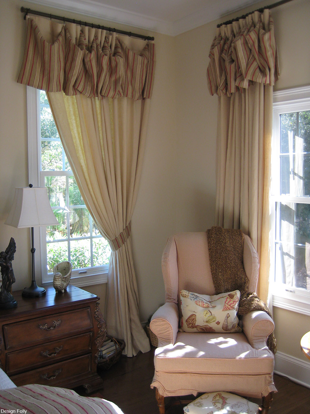 armchair by two windows with drapes