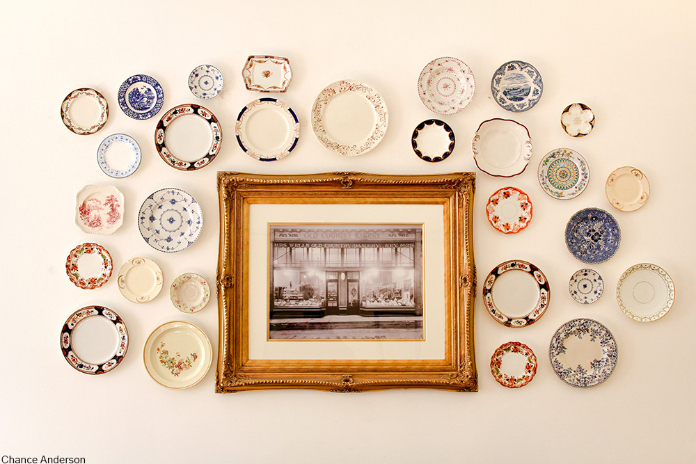 collection of plates hanging on a wall with a gold-framed photo