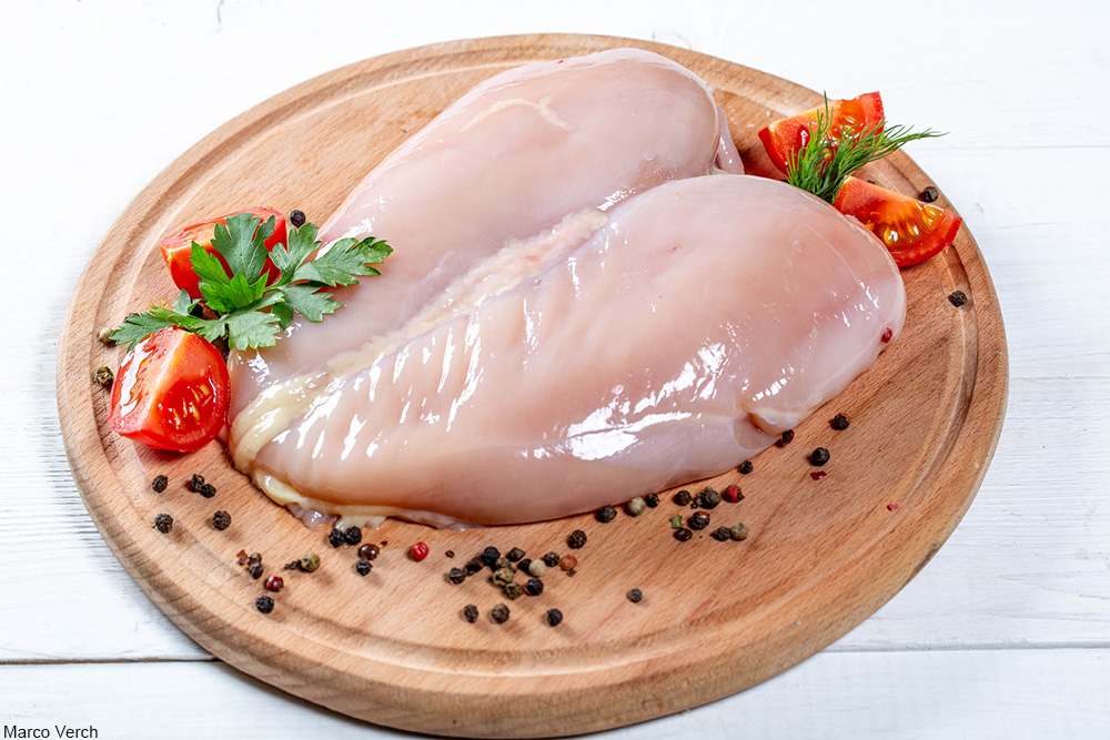 raw chicken breast surrounded by peppercorns