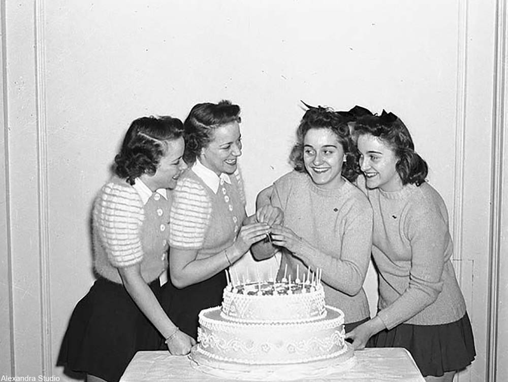 teenaged girls with a birthday cake in the 1950s