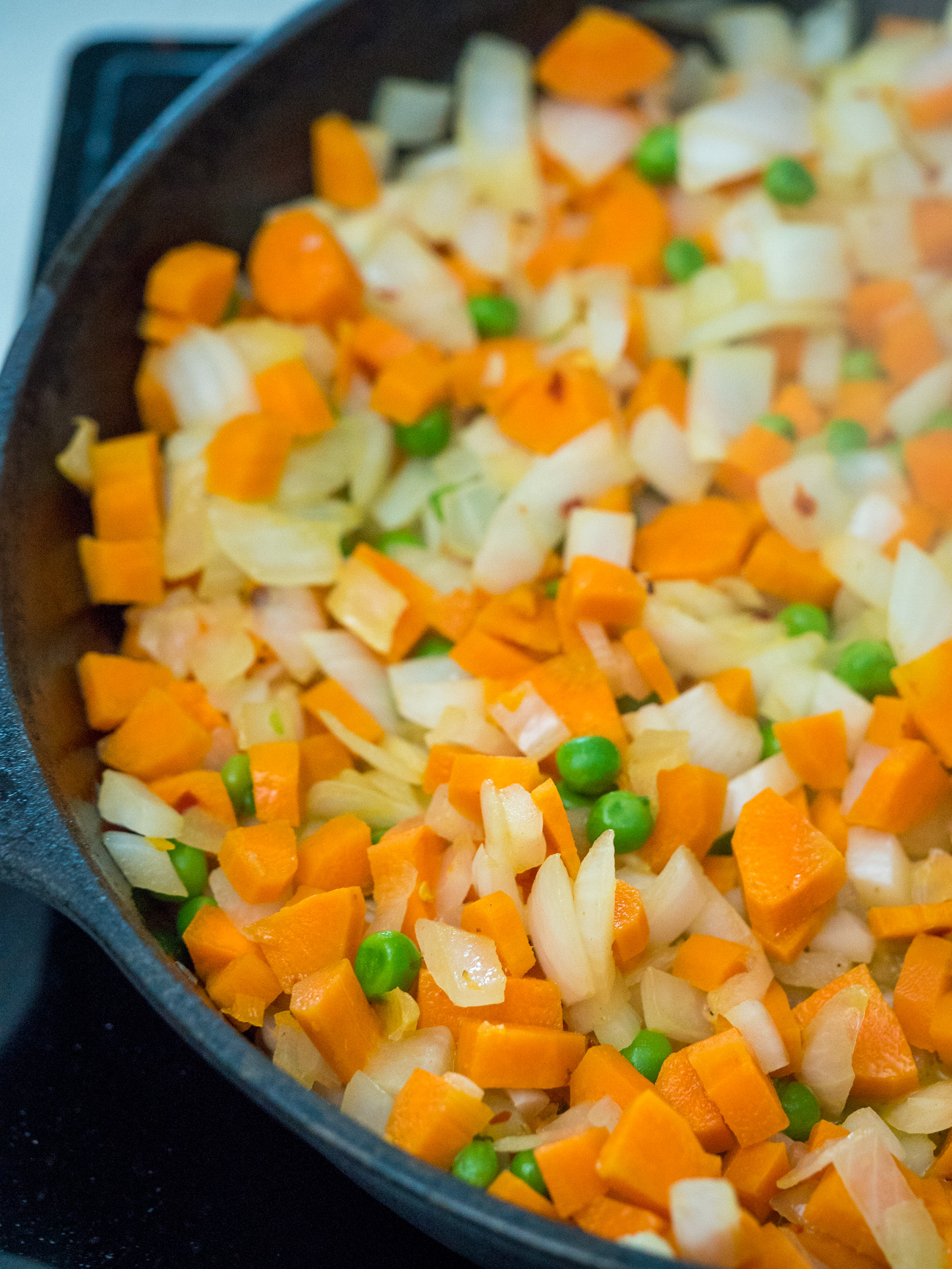 While the rice is cooking, heat butter in a large skillet. Add onion, garlic, ginger, peas, carrots, and salt & pepper. Cook over medium-high heat for 5-7 minutes.