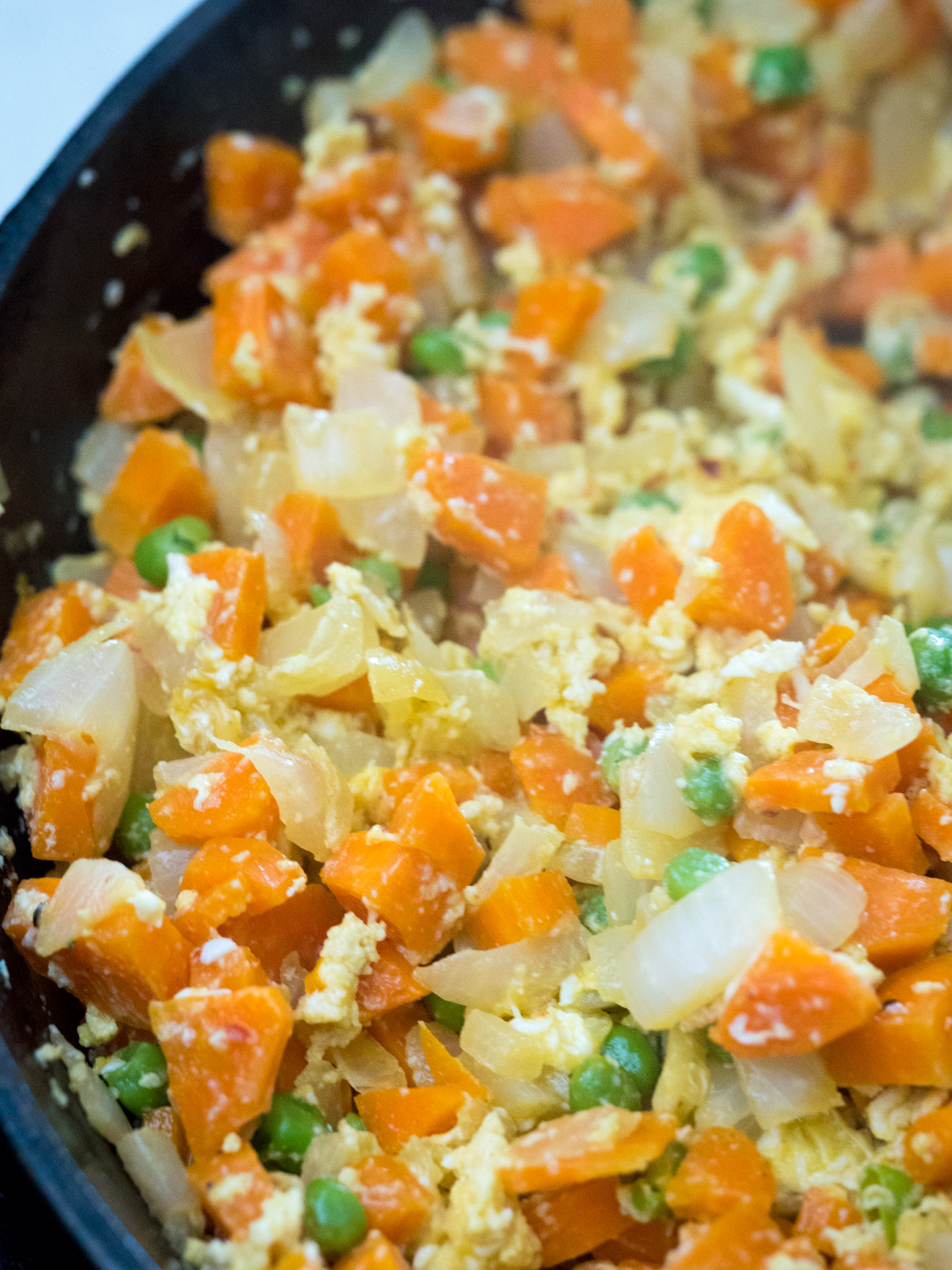 Crack eggs into pan and scramble, mixing with vegetables.
