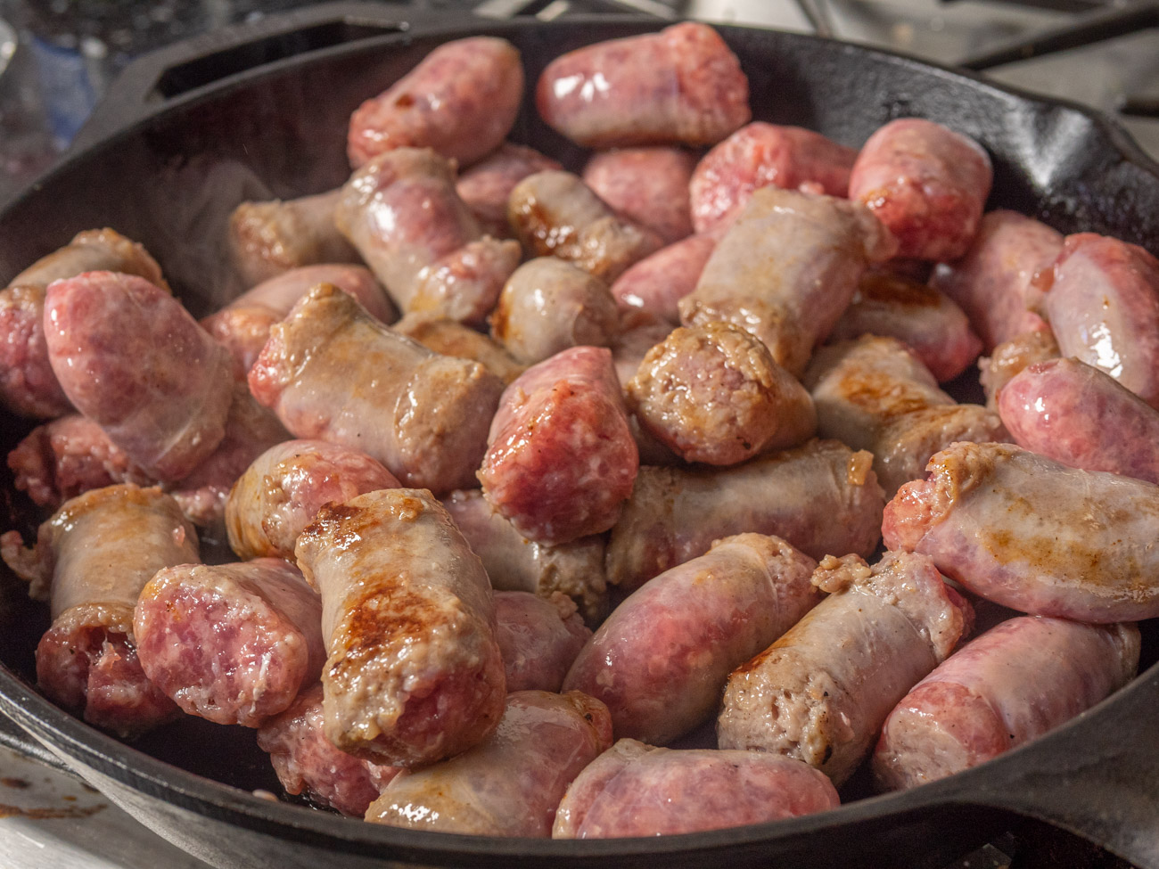 Cut bratwursts into thirds. Pour 1 tablespoon of olive oil into a large skillet. Over medium heat sear the brats to brown the outside. Place cooked brats in a 9x13 casserole dish.