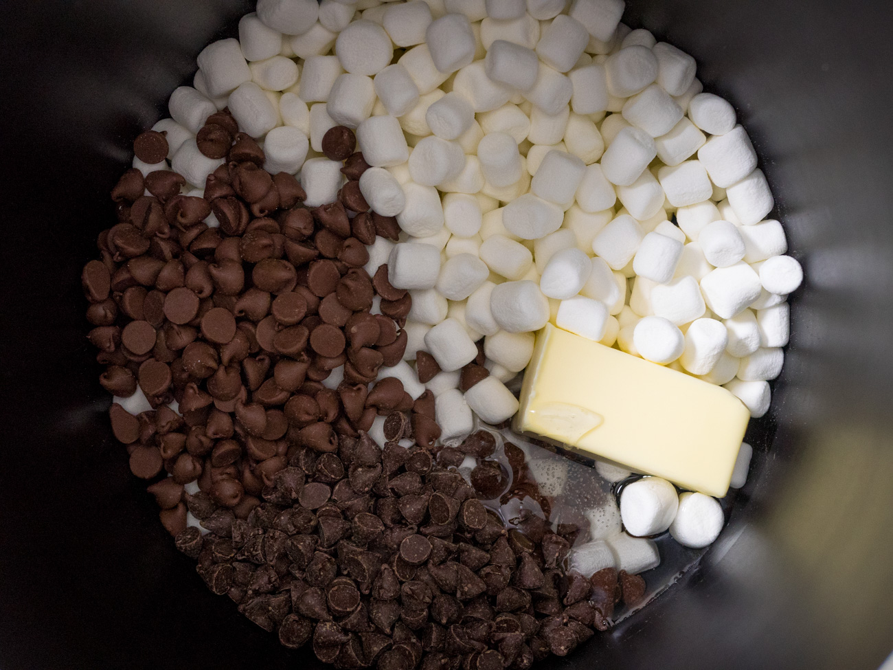 In a large saucepan, mix 4 cups of marshmallows, both kinds of chocolate chips, butter, and corn syrup. Stir mixture over medium heat until melted.