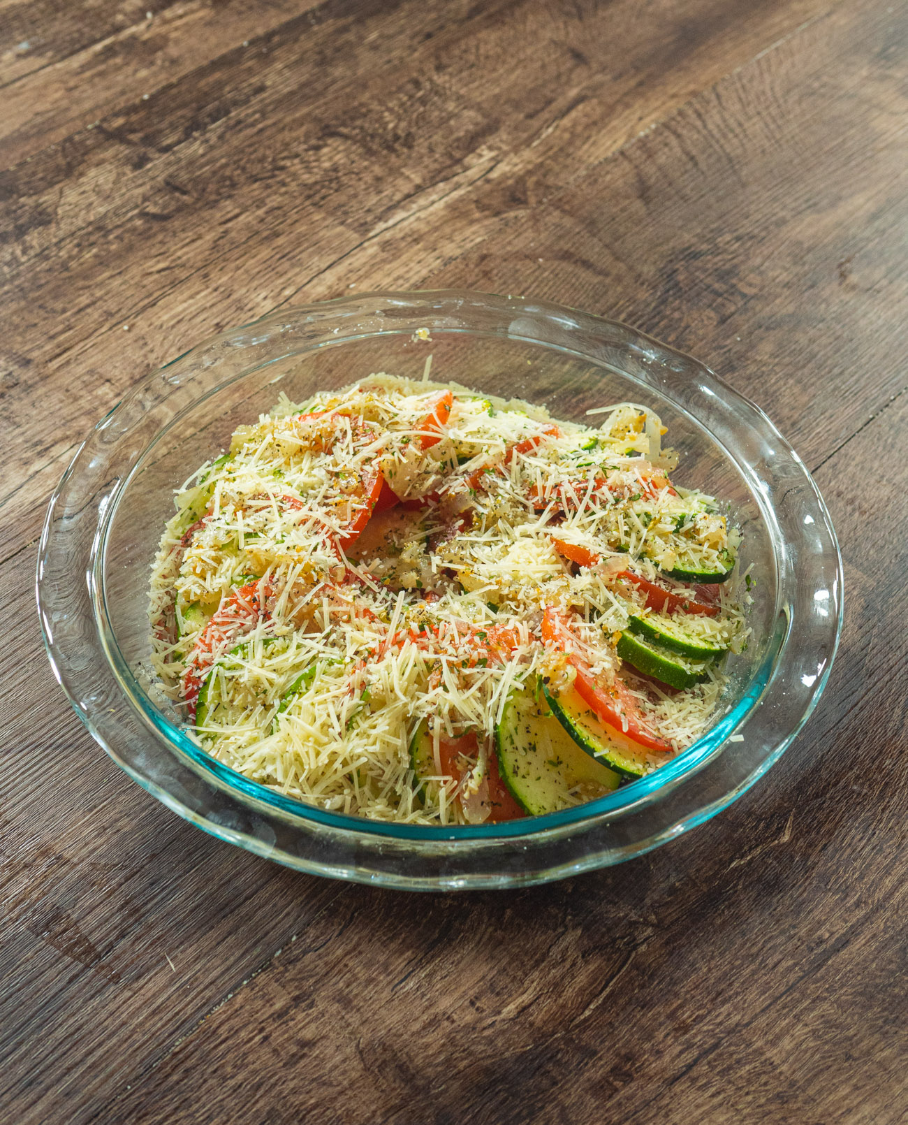 Top with remaining onion-garlic mixture. Drizzle with olive oil and sprinkle with oregano, basil, parsley, salt, and pepper. Top with the shredded Parmesan cheese.