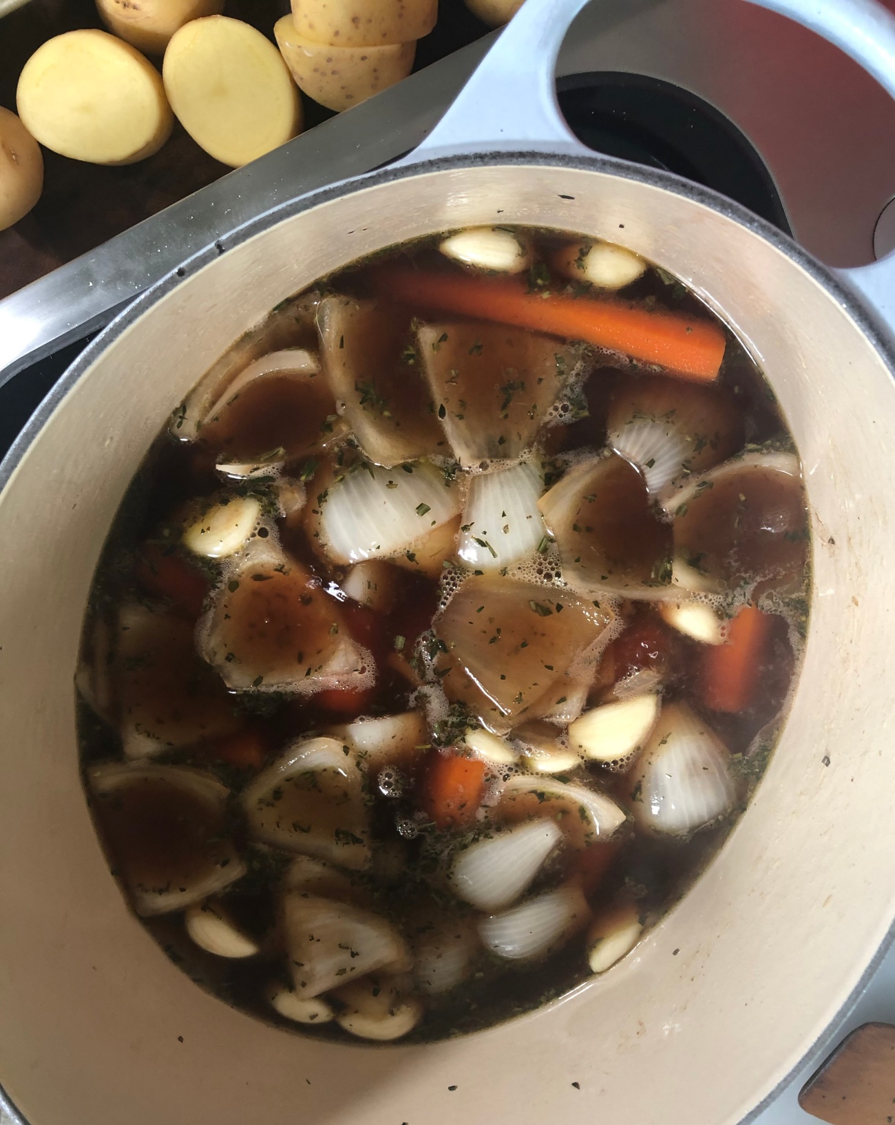 Once wine is reduced by at least half and the bottom is scraped clean, add carrots and onions back to pot. Place the brisket on top, then add the beef stock.