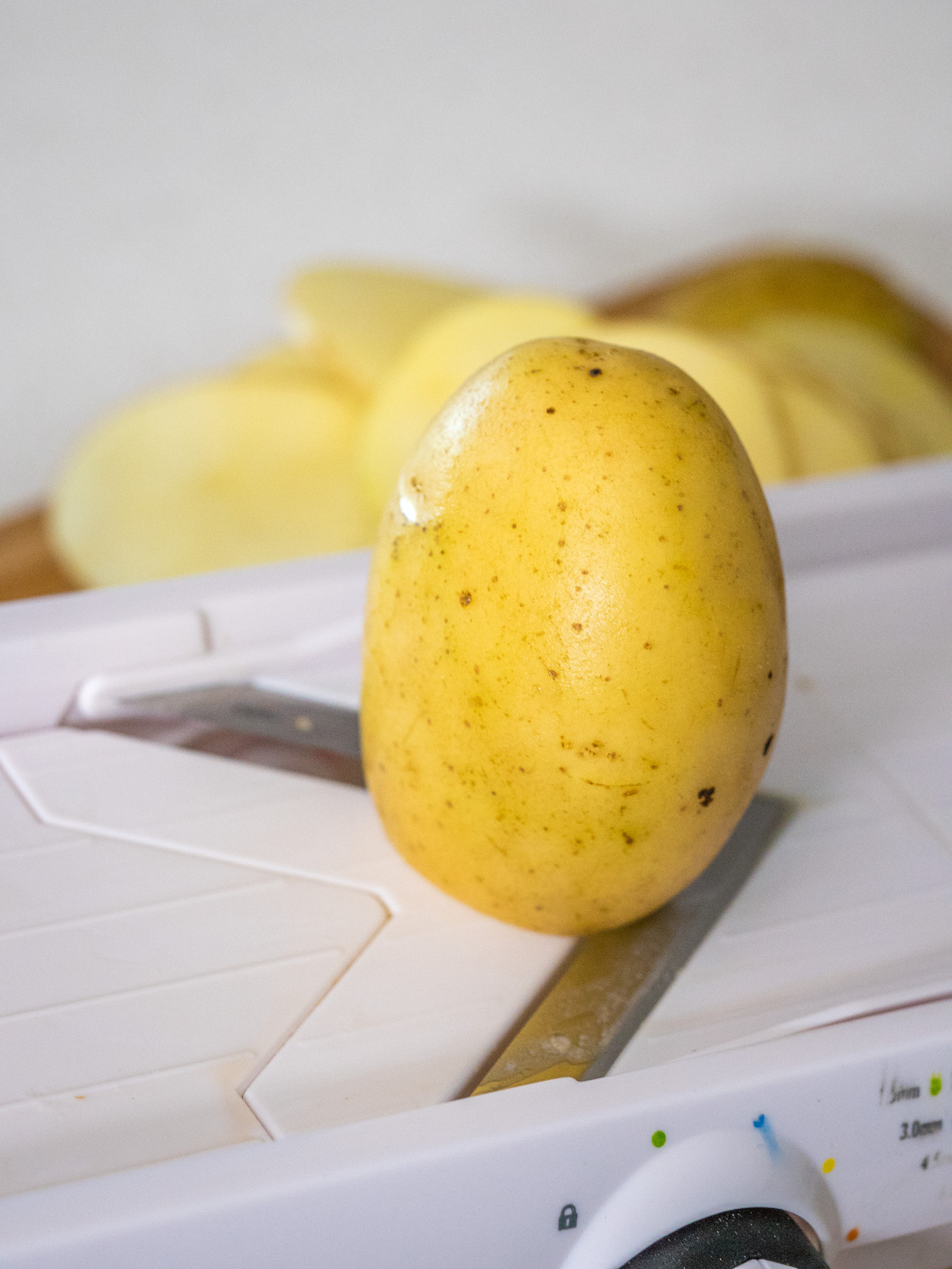 potatoes being sliced on a mandoline