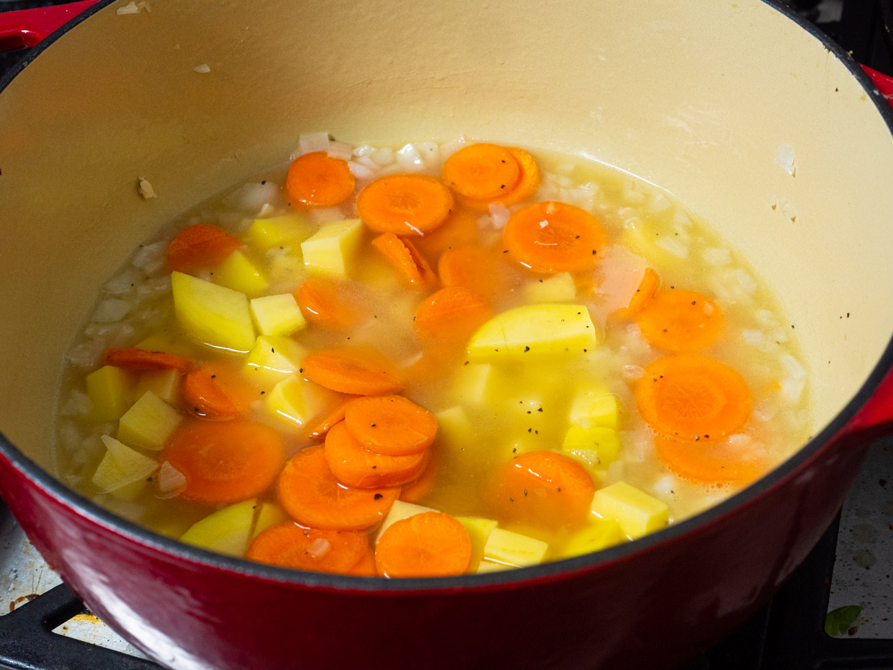 Stir in carrots, potatoes, chicken broth, salt, and pepper. Bring to a boil. Once boiling, cover with a lid and reduce heat to medium-low. Cook for 15 minutes.