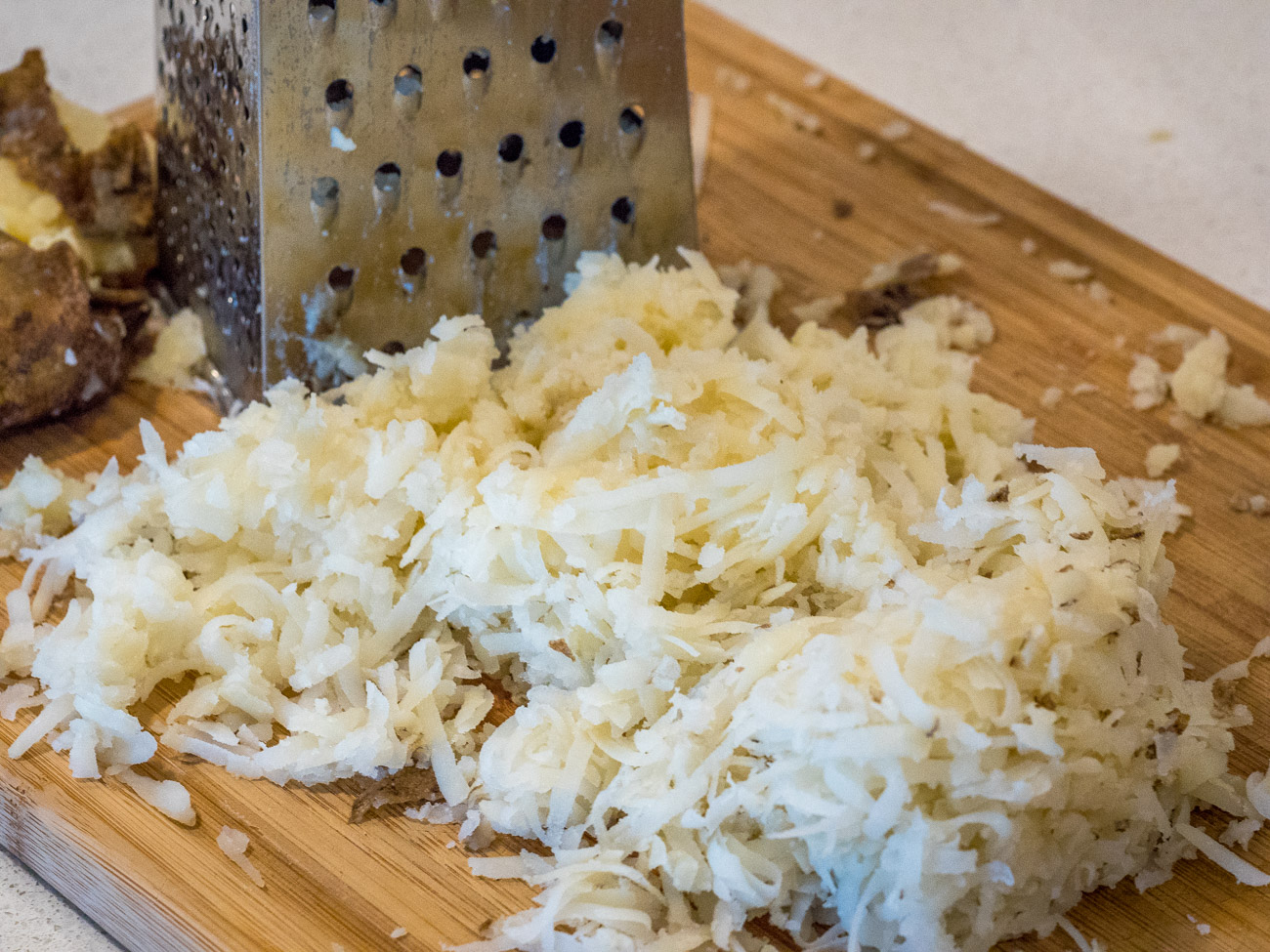 Preheat the oven to 350ºF. Grate potatoes using large holes on box grater. Do not peel potatoes before grating.
