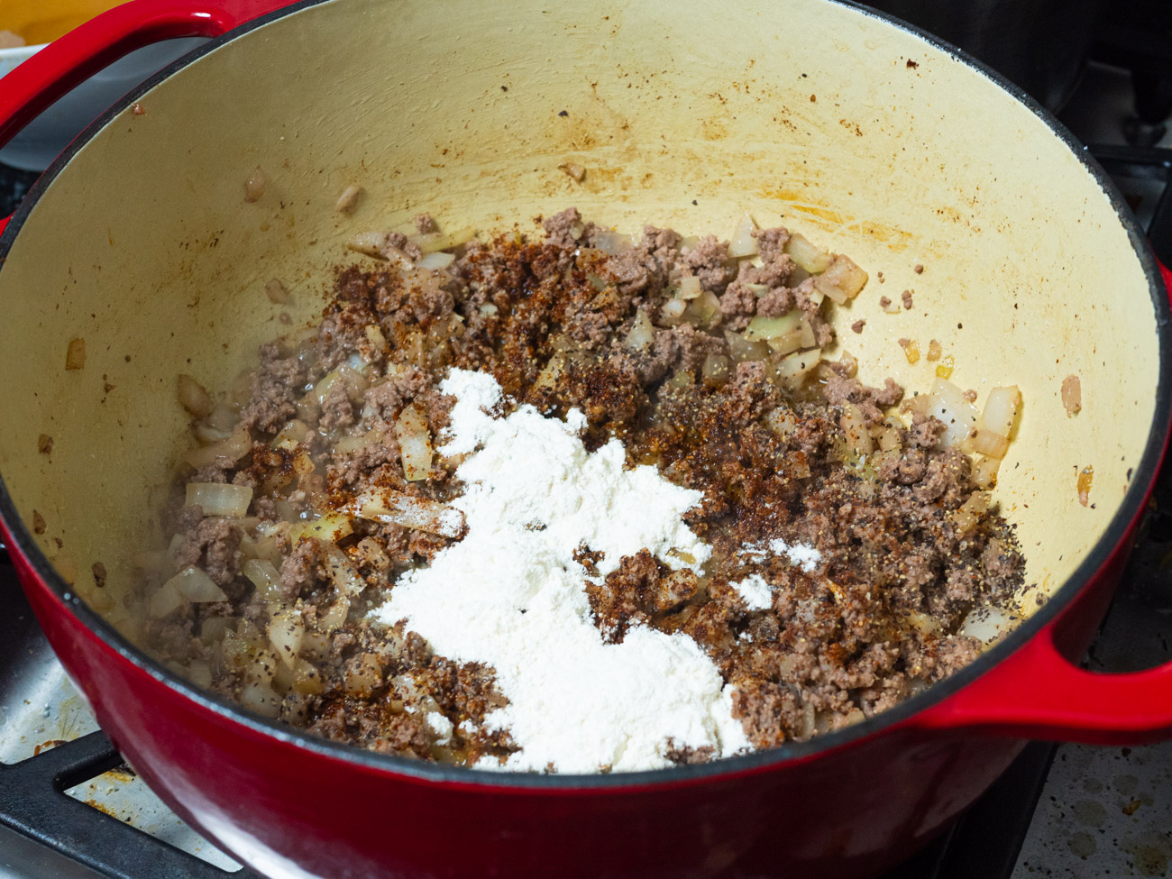 Season with salt and pepper, and sprinkle flour and chili powder over beef. Stir and cook 1 minute.