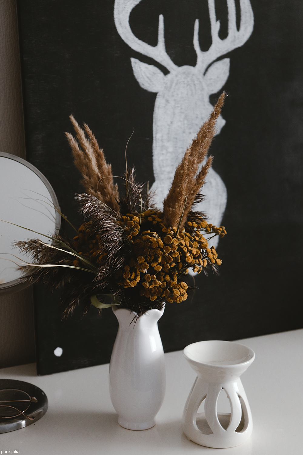 white vase filled with dried flowers and grasses