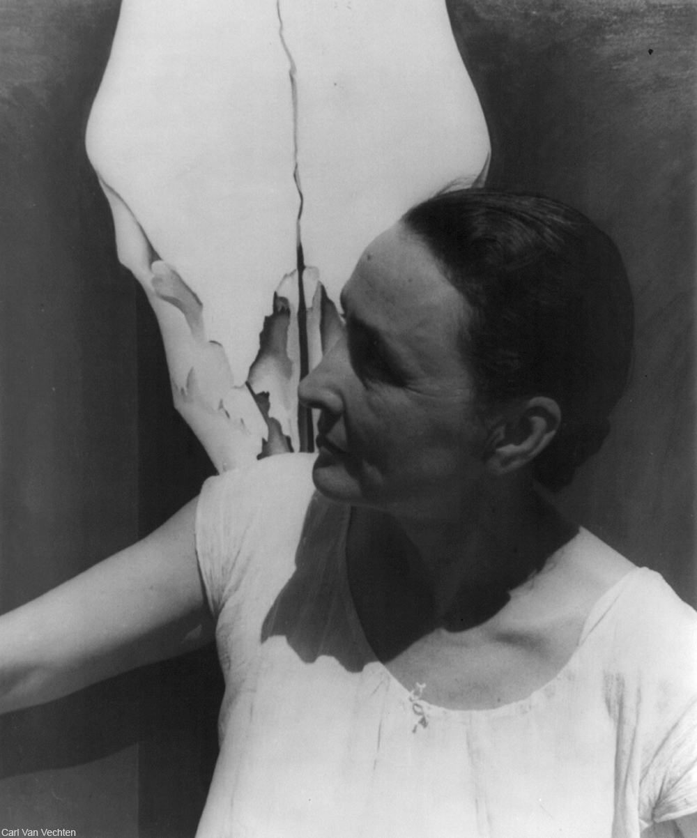 Georgia O'Keeffe photographed in front of one of her paintings