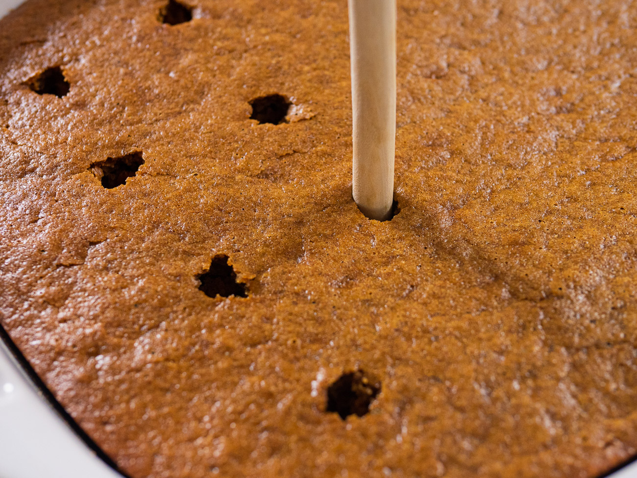 Using a straw or wooden spoon handle, poke holes into the cooled cake.