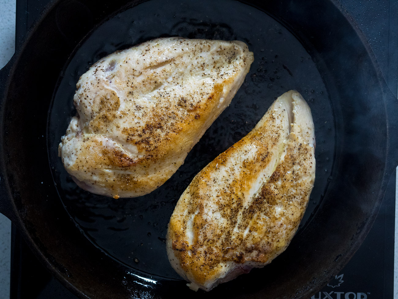 Pat chicken breasts dry and season with salt, pepper, and garlic powder. Heat oil over high heat and quickly sear chicken breasts on both sides.