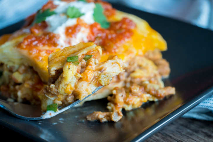 Serving of burrito casserole on a plate with sour cream on top