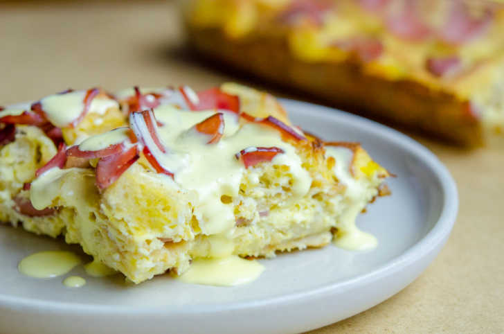 Close up of a serving of eggs benedict casserole with bacon and cream on top