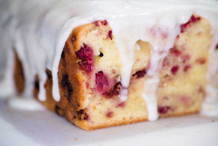 Close up of raspberry bread loaf with lemon icing drizzling down