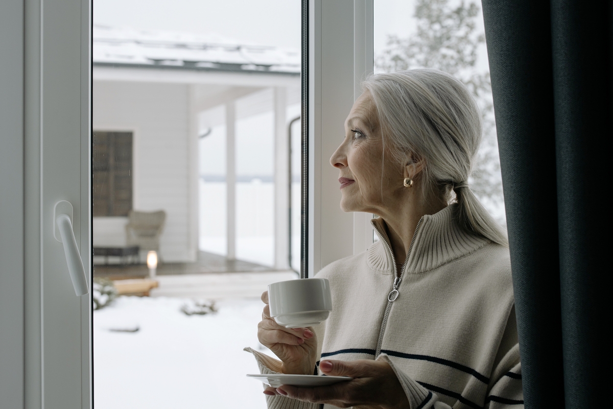 woman with silver hair sitting at a window 