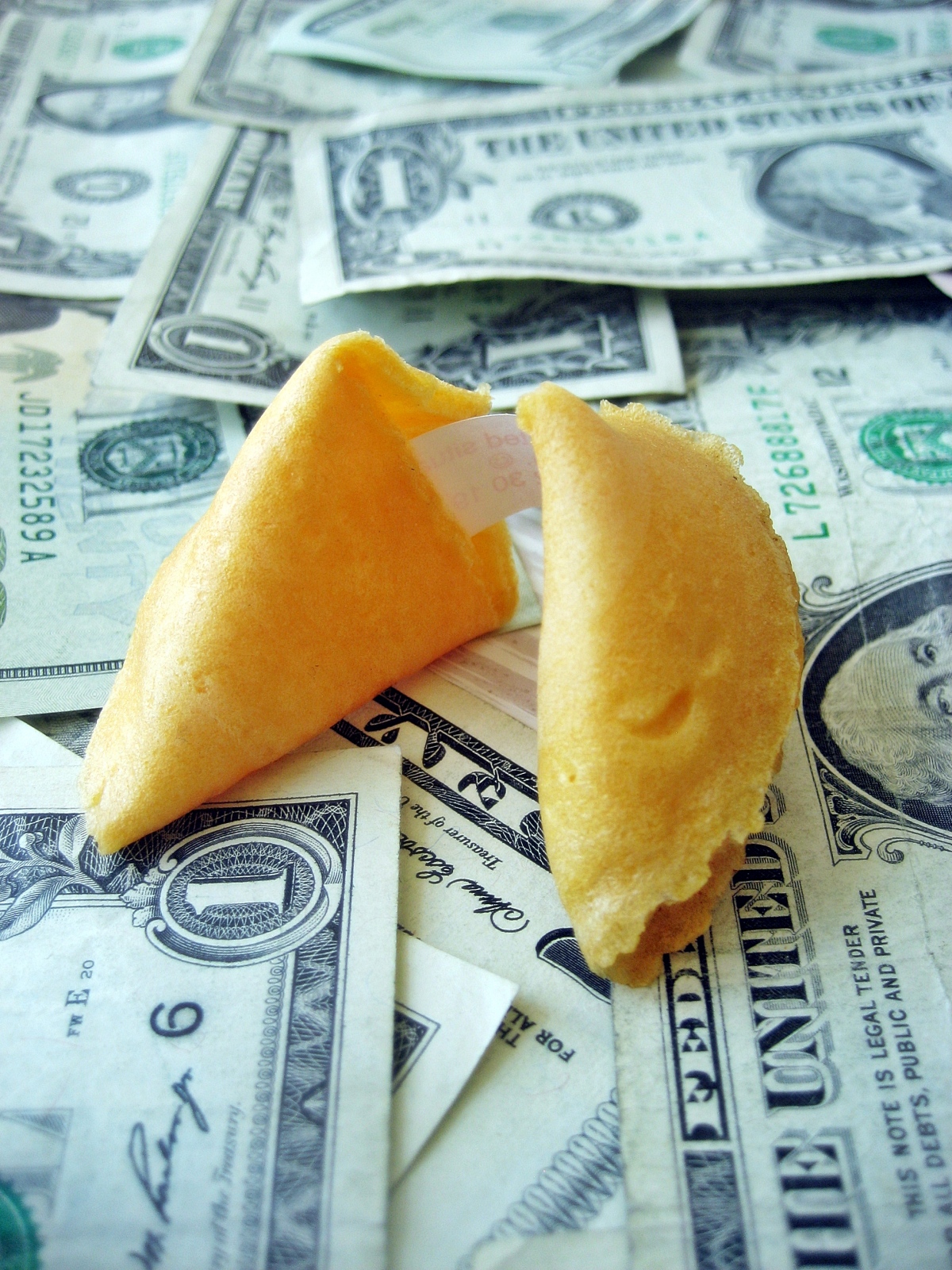 fortune cookie sitting on a pile of money