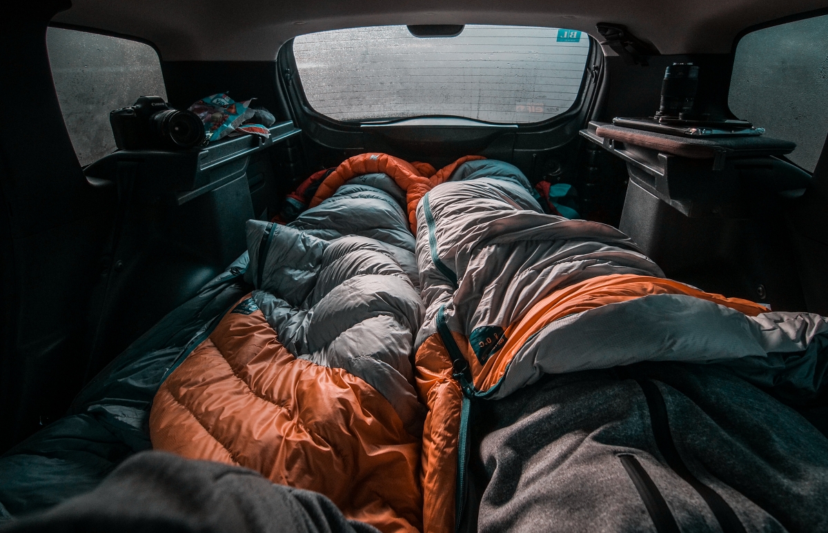 two people in sleeping bags in the back of a car