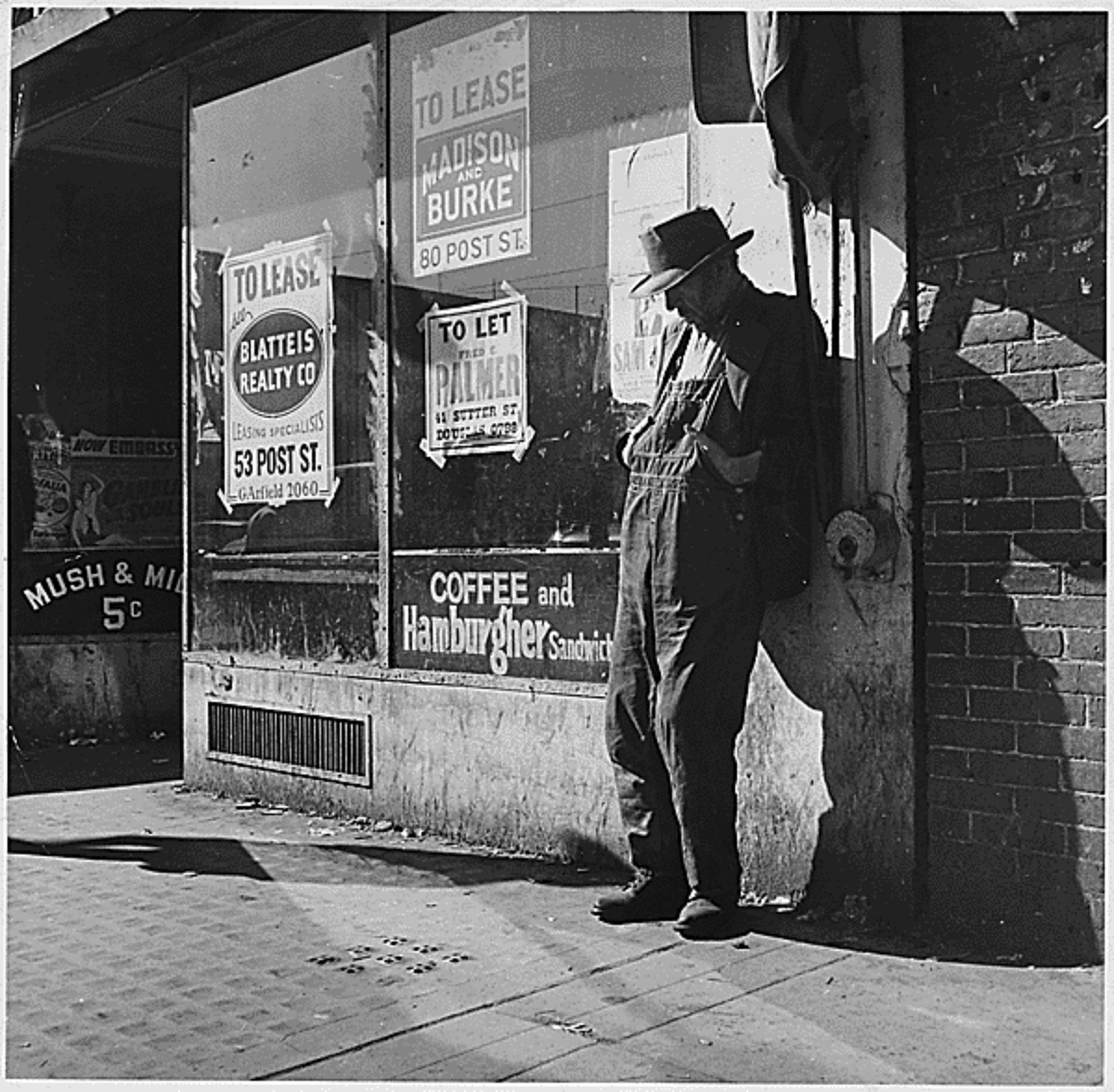 unemployed man loitering outside a shuttered general store, 1935
