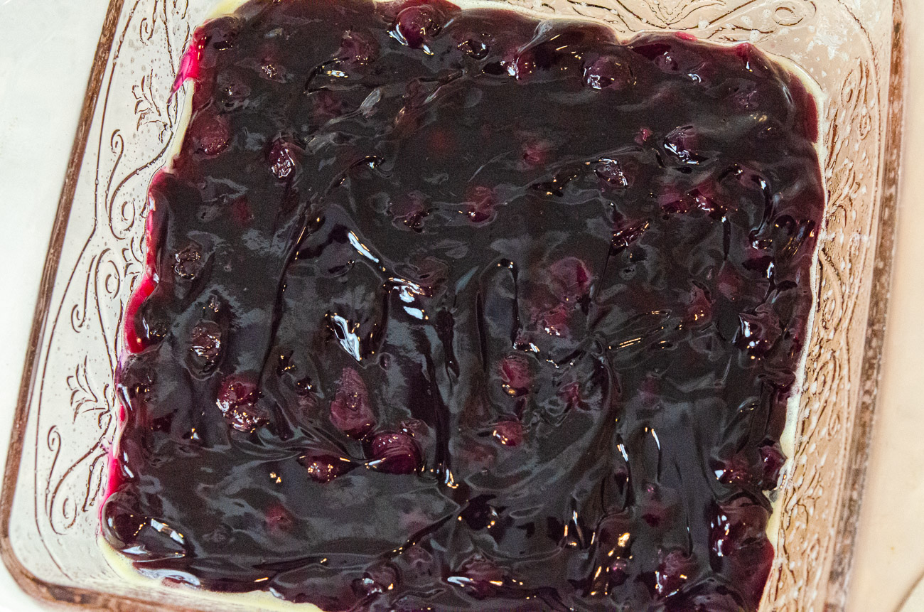 Pour blueberry pie filling into bottom of baking dish, taking care to spread it into the corners.