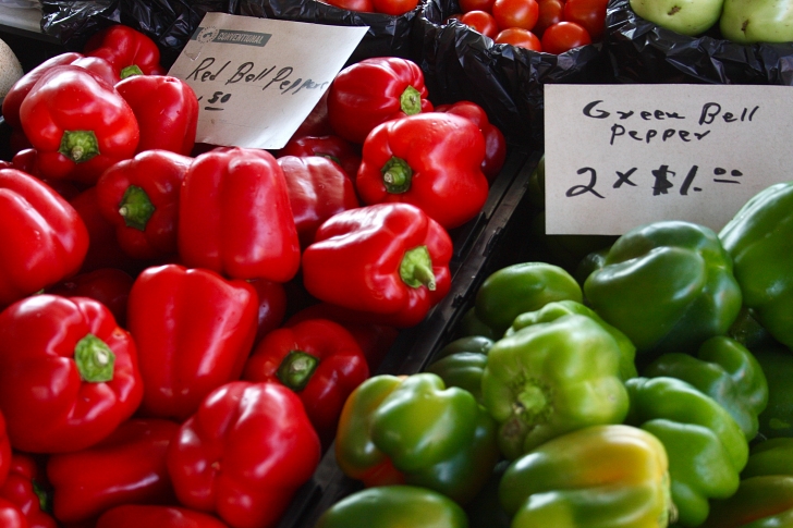 red and green bell peppers being sold in a market