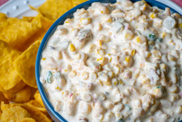 CLose up of creamy corn dip with chips in the background