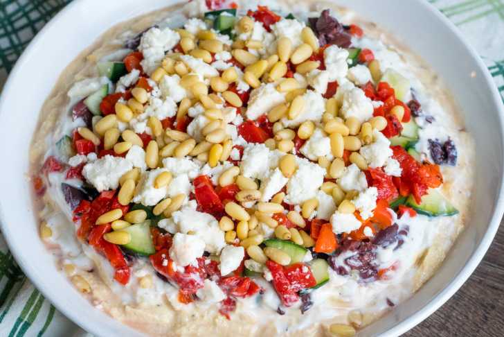 Close up of colorful Greek seven layr dip in a round, white dish