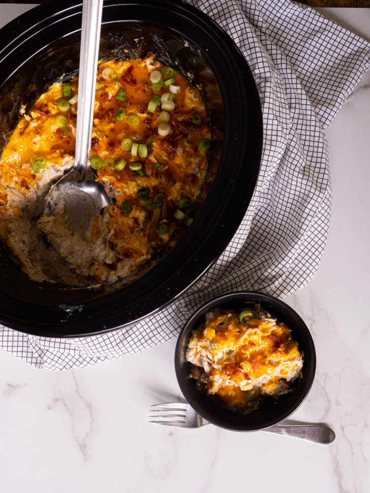 Top down of a slow cooker and a bowl of cheesy chicken and bacon