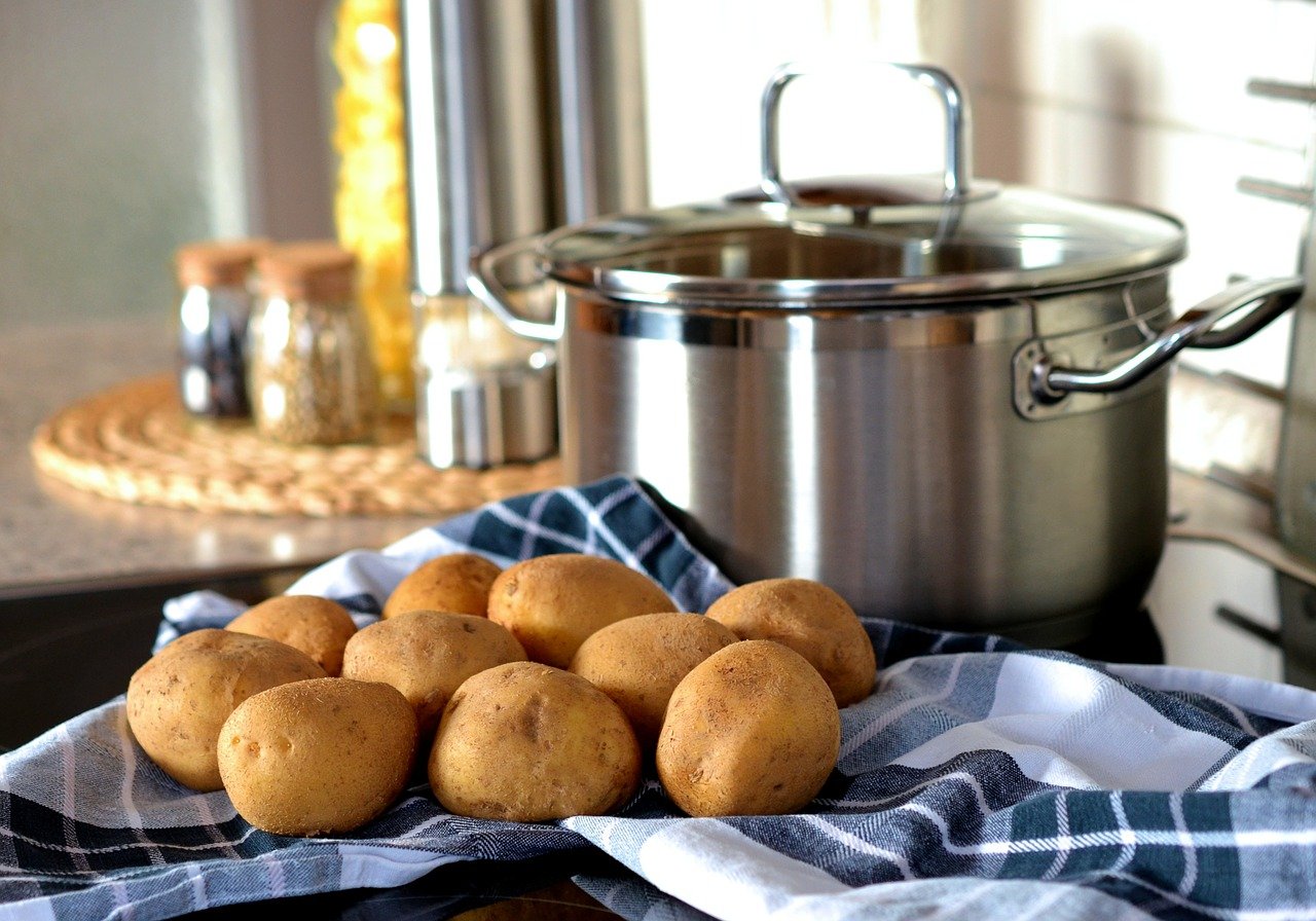 Potatoes next to a pot sitting on a counter