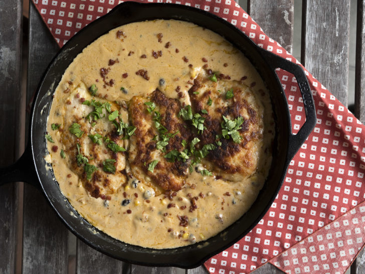 Top down of chicken breasts in a skillet with sauce on top