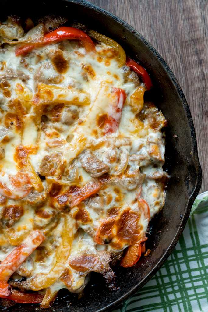 Top down of a skillet with beef, peppers, and cheese