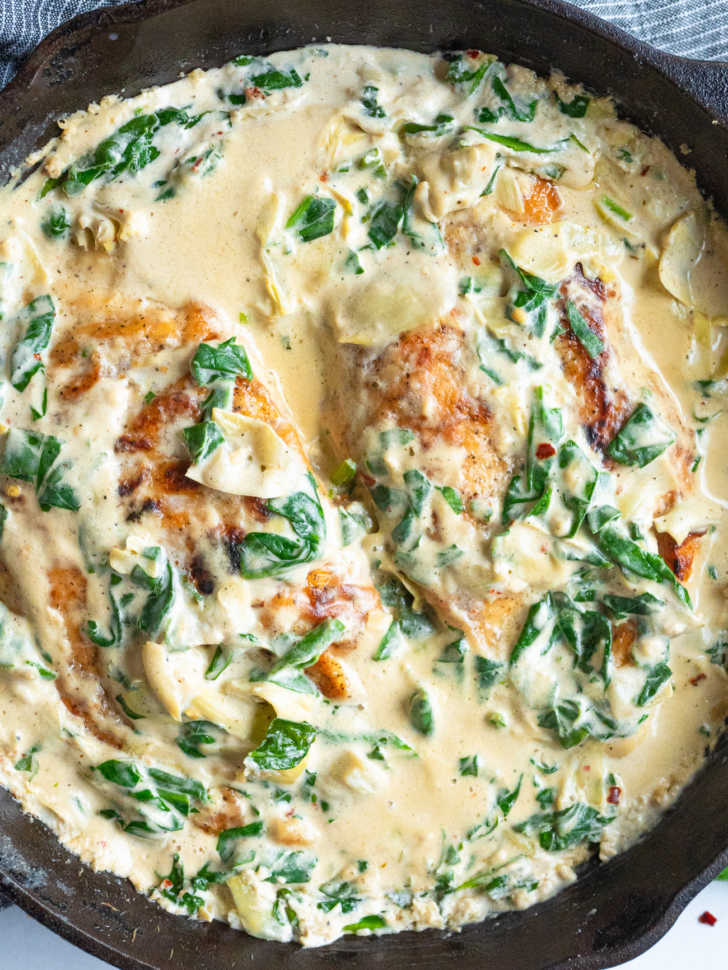 Top down of chicken in a skillet with creamy sauce