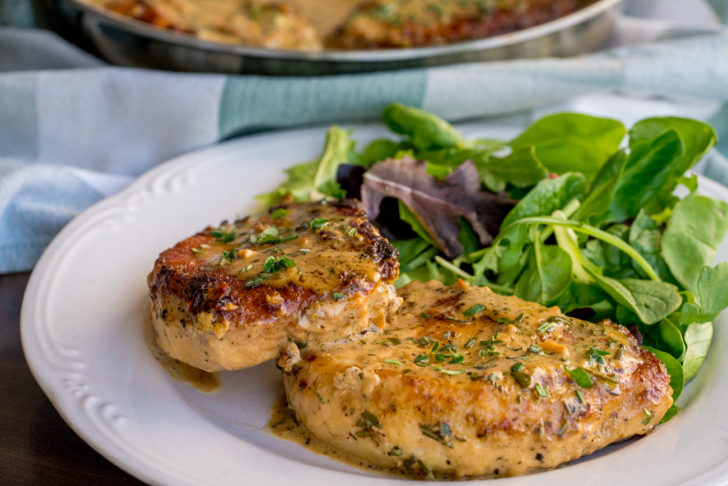 Side view of creamy pork chops on a plate