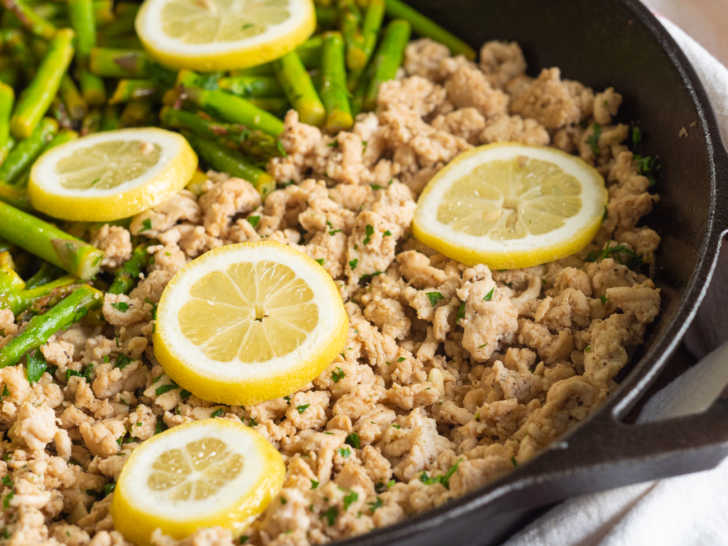 Close up of ground turkey, asparagus, and lemon slices in a skillet