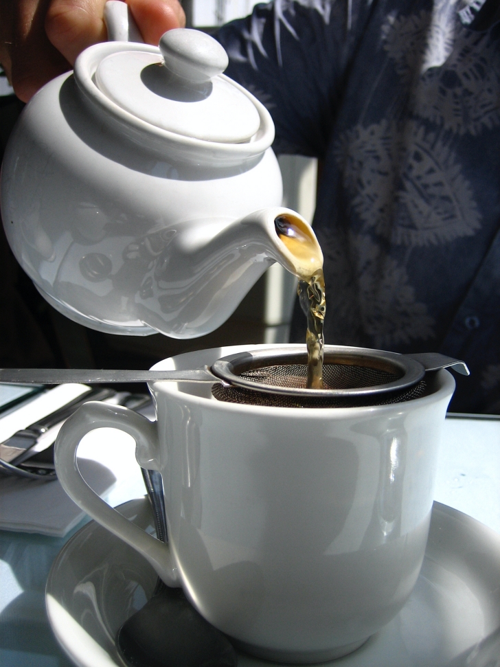 tea being poured into a teacup from a teapot