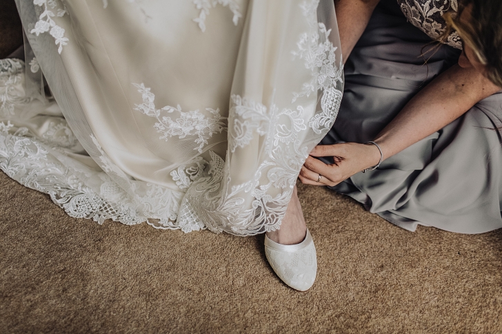 bridesmaid prepares bride for wedding