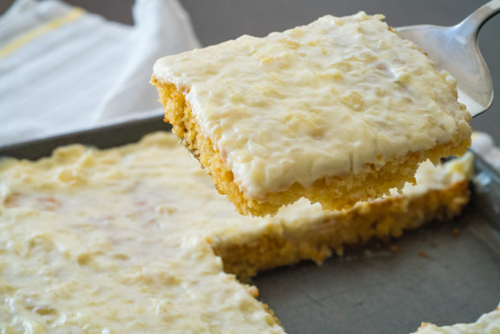 Pineapple sheet cake with a piece lifted out