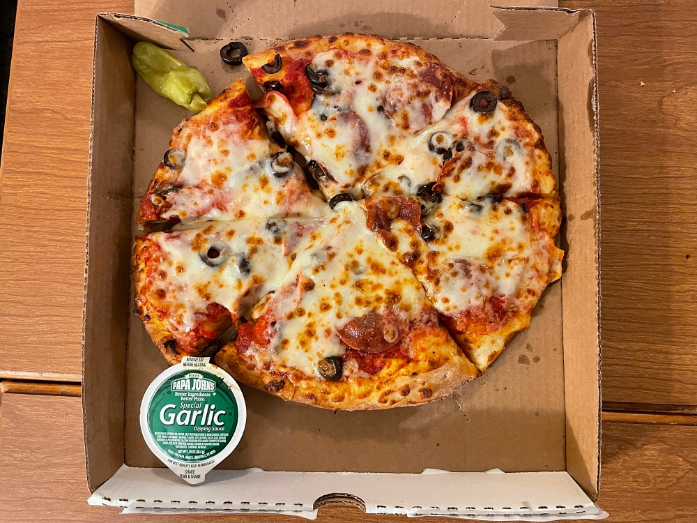 pizza in delivery box with tub of garlic butter