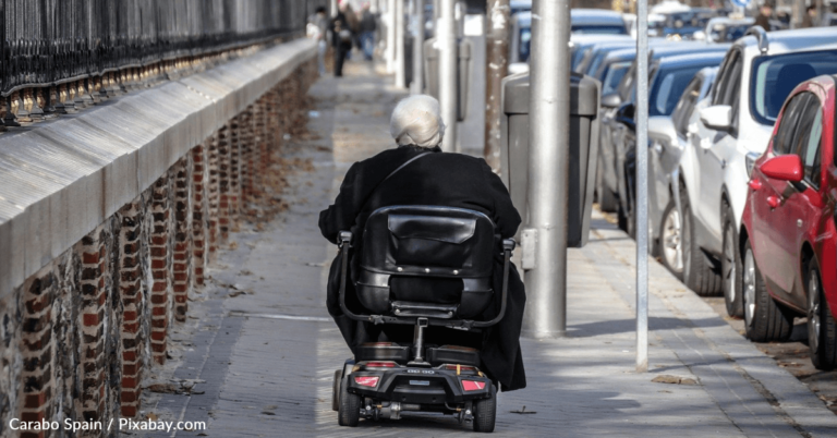 Young Men Help Push An Elderly Woman Riding A Scooter In The Rain
