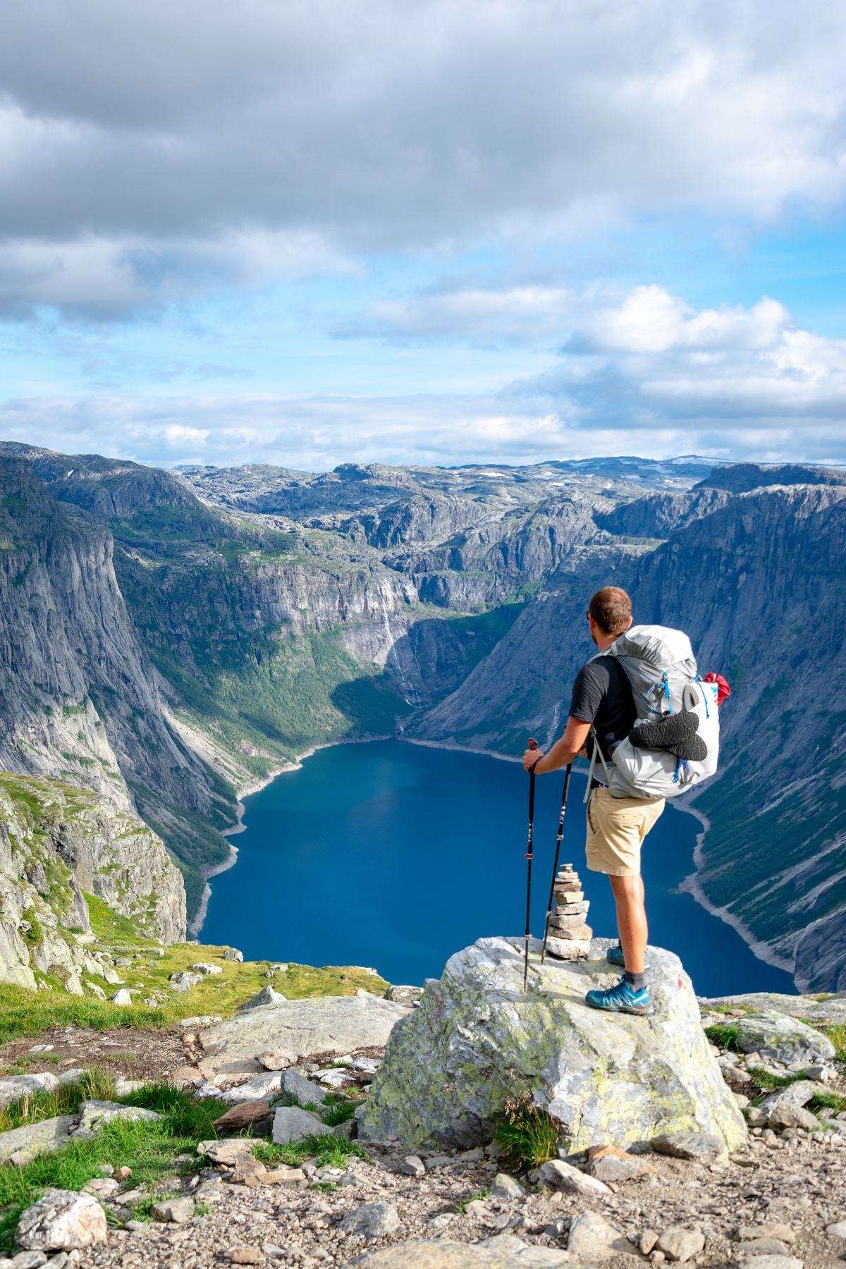 hiker with walking sticks aside a small cairn