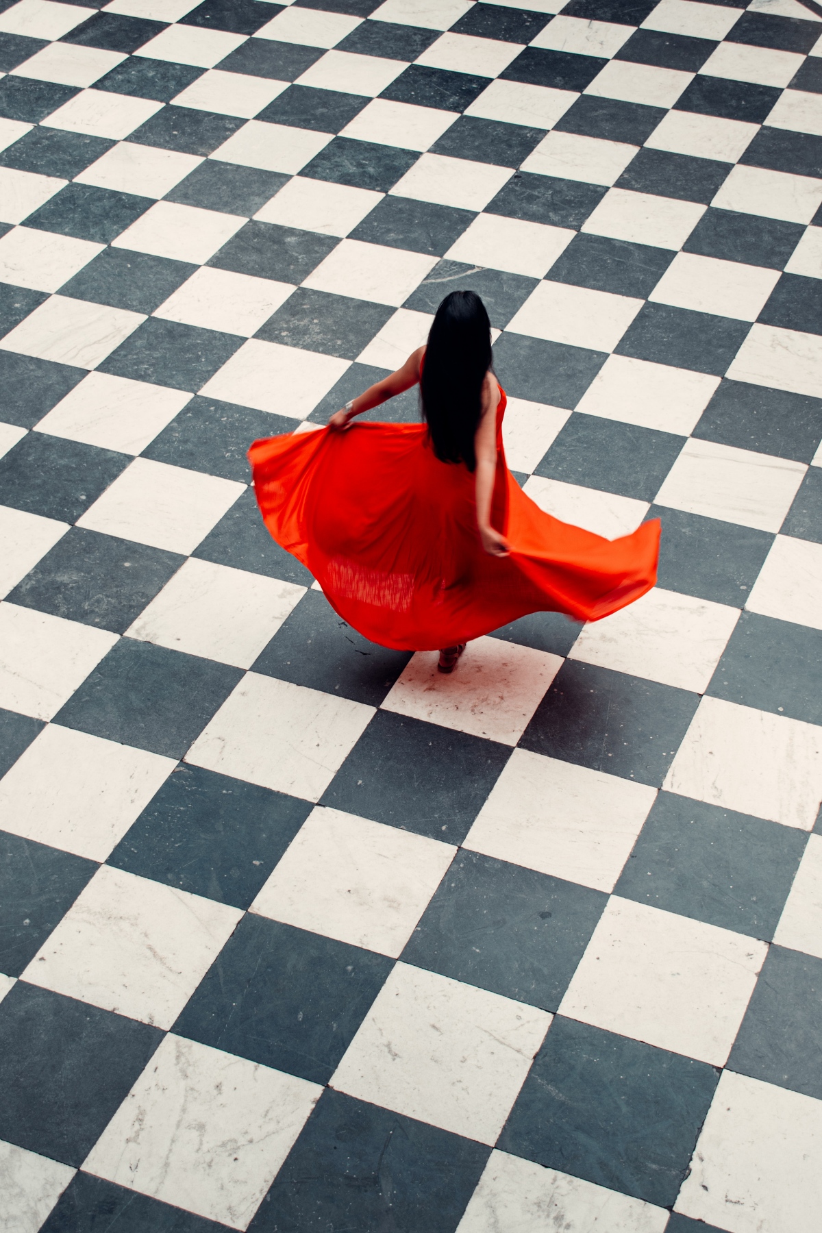 woman in red dress on black and white tiles